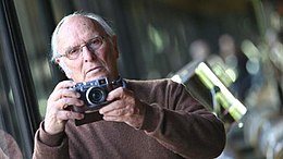 Ein Porträt von Carlos Saura mit einem Fotoapparat in der Hand aus dem Jahr 2017