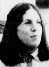 A grainy, black-and-white photo of a white woman with shoulder-length dark hair, looking to the right of the camera
