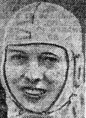 A black and white photograph of a woman in racing overalls typical of the 1930s