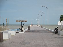 An image of a boardwalk over a body of water. A sign says "Chicxulub Puerto Mexico"