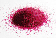 a pile of red granules on white paper