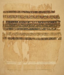 Photo of a ragged white piece of fabric with woven bands of decoration