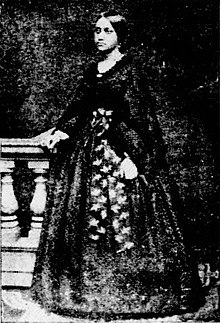 Black and white full-length photograph of a 19th-century woman in Western dress