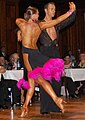 Image 5Latin dancers in their costumes. The woman is wearing backless dress with deep slits on its lower portion, while the man is wearing a shirt with top buttons open. (from Fashion)