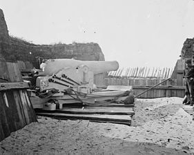A nine-inch (229 mm) Union navy Dahlgren gun set up on land for siege work as they were at battery ten at Port Hudson. The gun is whitewashed so it can be more easily worked at night. The projections at the breech are for the navy double vent percussion firing system. The crewman at the far right is wearing the Union navy uniform.