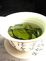 Green tea leaves steeping in a gaiwan