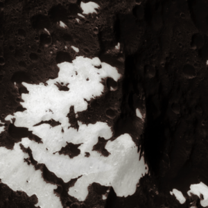 A super-close image of Iapetus's transition area between its light and dark side, showing white materials sharply spattering into the dark materials. Imaged by Cassini on September 10, 2007, at a distance of 9,240 kilometers (5,740 miles) somewhere in the area of the Carassone Montes.[59]