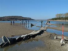 View of a river winding past a sandbar with people on the shore