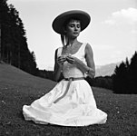 Hepburn in a light belted a-line sundress and straw hat in Switzerland, c. 1954
