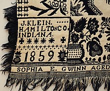 Dark blue and white, double jacquard coverlet with self fringe approx. 2.25" on two sides and bottom. Top is hemmed. Two trade blocks reading "J. Klein / Hamilton Co. / Indiana / 1859''. Woven below is "Sophia E. Gwinn Aged 16". Floral baskets border on three sides. Side borders have two rows of stars below the baskets. Field has floral medallions and eight pointed stars
