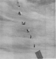 A vintage military photo shows a string of balloons and reflectors stretching into the sky.
