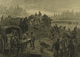 A vicar stands at an open grave, which is being filled with a coffin. Several others are being unloaded from a covered waggon. Crowds of people are shown paying their respects.
