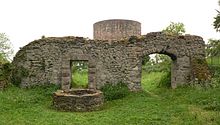 Photo of a ruined stone walls and a circular tower in a meadow