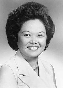 Photographic portrait of a smiling Asian woman in a sleeveless blouse