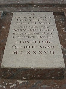 A stone slab on the ground with carved lettering on it
