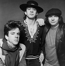 A black and white photograph of three men, one is wearing a wide-brimmed black hat.