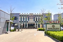 A modern building with a glass and metal façade, the words "Capri-Sun" and Chinese text toward its top. On the road leading to it, a sign bearing Chinese text and the translation "Bestshin Beverages (Beijing) Co., Ltd."