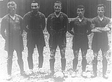 Five players in uniform, standing in front of a ball