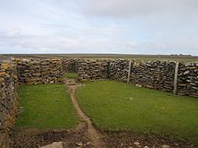 An area surrounded by dry stone walling with a gate at one end to keep sheep enclosed.