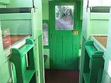 A view of the inside of a caboose with railroad track visible through one of its windows