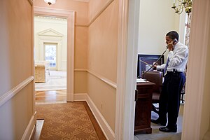 Barack Obama in the Oval Office Study; the interior of the Oval Office can be seen through the open door