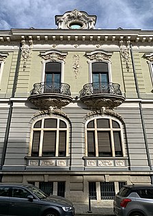 Complex wrought iron papo-de-rola balconies with elaborate Rococo Revival shells and round shapes (aka volutes) under them, on the facade of Strada General H. M. Berthelot no. 41, Bucharest, unknown architect, 1911[57]