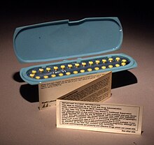 An oblong blue container holding 28 yellow pills, with a small, folded paper note standing in front of it