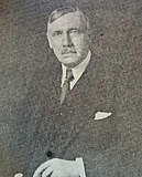 A black-and-white photograph of a man in a suit with a tie