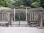 Stone lanterns and torii behind stone fence.