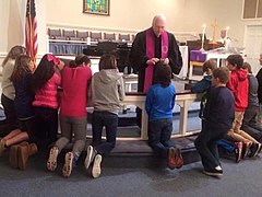 A Methodist pastor distributing ashes to confirmands kneeling at the chancel rails, 2016