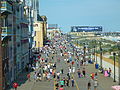 People walking along a wide pathway near the ocean on a sunny day (from New Jersey)