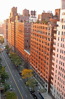 Several multi-story apartment buildings lining East 57th Street, a six-lane road, between First Avenue and Sutton Place