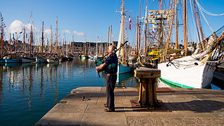 A man plays bagpipe in the harbour, during the international Celtic "Festival du chant de marin"