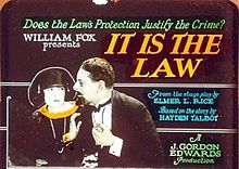 A man and woman in formal dress, with advertising text: 'Does the Law's Protection Justify the Crime? / William Fox presents It Is the Law / From the stage play by Elmer L. Rice / Based on the story by Hayden Talbot / A J. Gordon Edwards production'