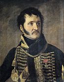 Painting shows a black-haired man with long sideburns and a moustache. He wears a dark hussar uniform
