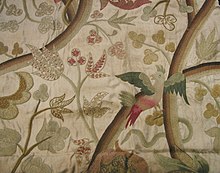 Multicolor design of leaves and a bird embroidered on beige fabric.