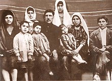 Black-and-white photo depicting four women, two men, and three young children