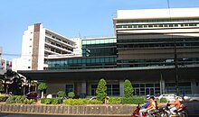 A modern building, with motorcyclists in front for scale