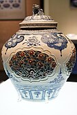 Yuan dynasty blue and white pottery decorated in fretwork floral designs (lotus petals, grasses, and peonies) in blue and red glaze with a lion finial on the lid