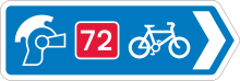 A blue direction sign with a right-pointing arrow. Three symbols (ranged left to right) are; a Roman soldier's helmet, the number 72 written in white on a red background, and a bicycle symbol.