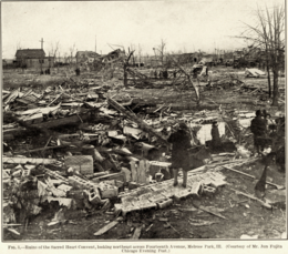 Black-and-white photograph depicting wreckage of building with twisted trees in the background