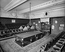 A snooker table with several rows of tiered seating around it