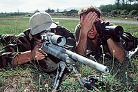 A spotter (right) uses a spotting scope to assist a marksman. Spotting scopes are used on target ranges to avoid walking to the target to verify the placement of hits