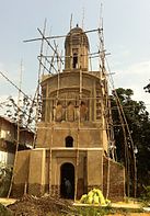 A brown domed structure with bamboo scaffolding