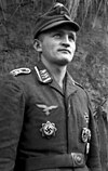 A man wearing a military uniform, field cap and various military decorations.