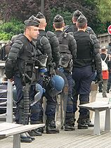 Riot control gear: body armour, shield, tear gas mask, apparatus for throwing tear gas canisters.