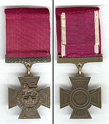 The obverse and reverse of the bronze cross pattée medal; obverse showing the crown of Saint Edward surmounted by a lion with the inscription "for valour" with a crimson ribbon; the reverse shows the inscription of the recipient on the bar connecting the ribbon with the regiment in the centre of the medal.