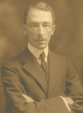 A sepia photo of a man in a suit with a tie.