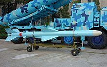 A blue missile in front of a launch vehicle with blue pixelated camouflage.