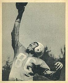 A black and white photo of Mann posing catching a football with one hand